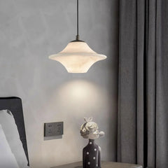 Modern alabaster pendant lamp with black accents hanging over bedside table with decorative polka dot vase