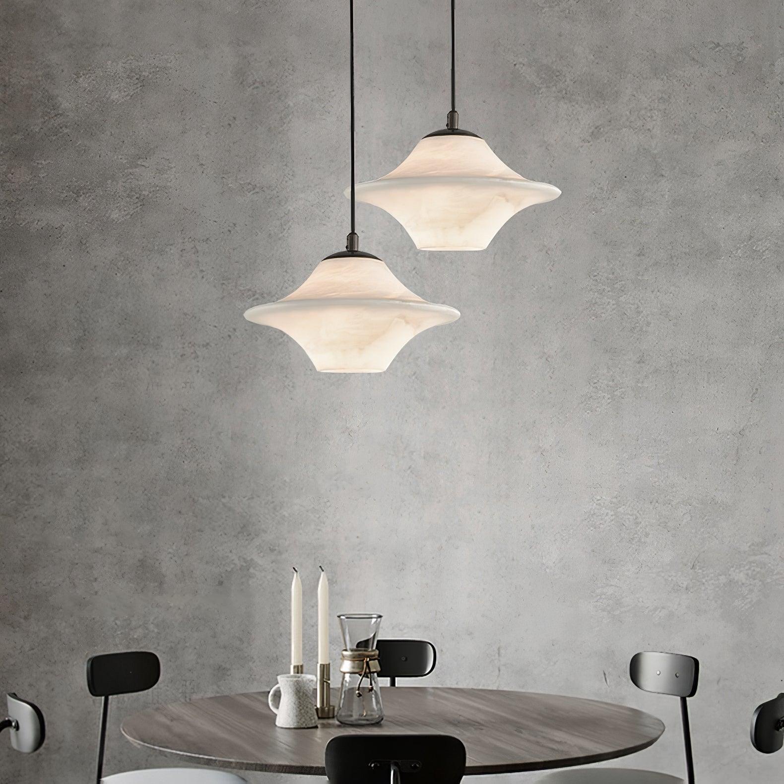 Modern black and white saucer alabaster pendant lamps hanging above a round wooden dining table with black chairs and candles