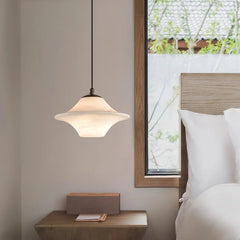 Modern black and white alabaster pendant lamp hanging beside a wooden bed and nightstand in a bedroom