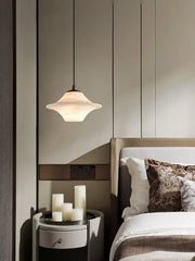 Modern bedroom corner with alabaster pendant lamp, round nightstand, and candles