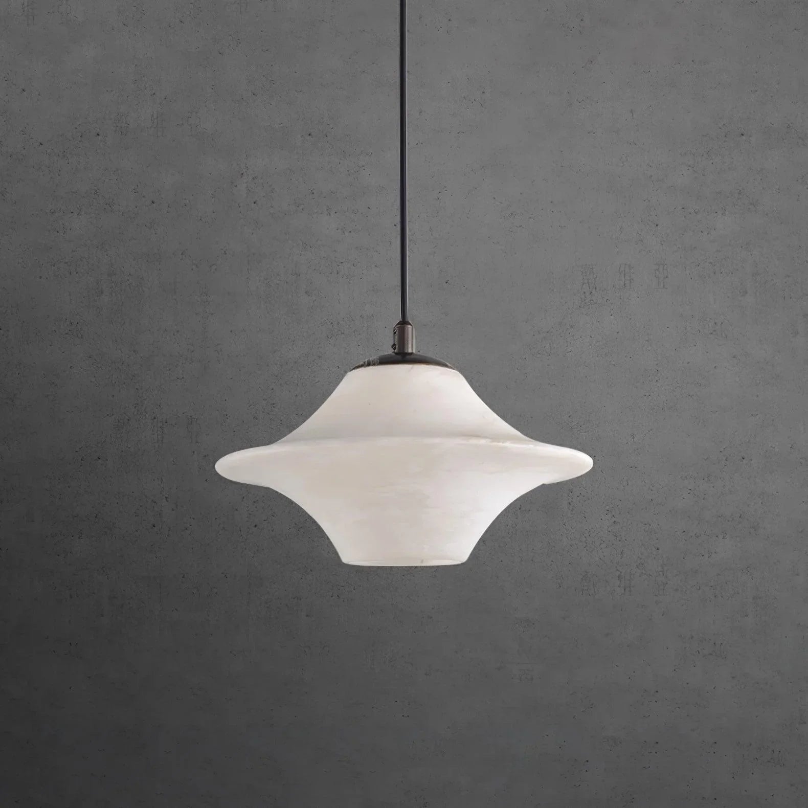 Modern white alabaster pendant lamp with black top and sleek design hanging against gray wall