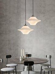 Modern dining room with round wood table, black chairs, alabaster pendant lamps and minimalist decor