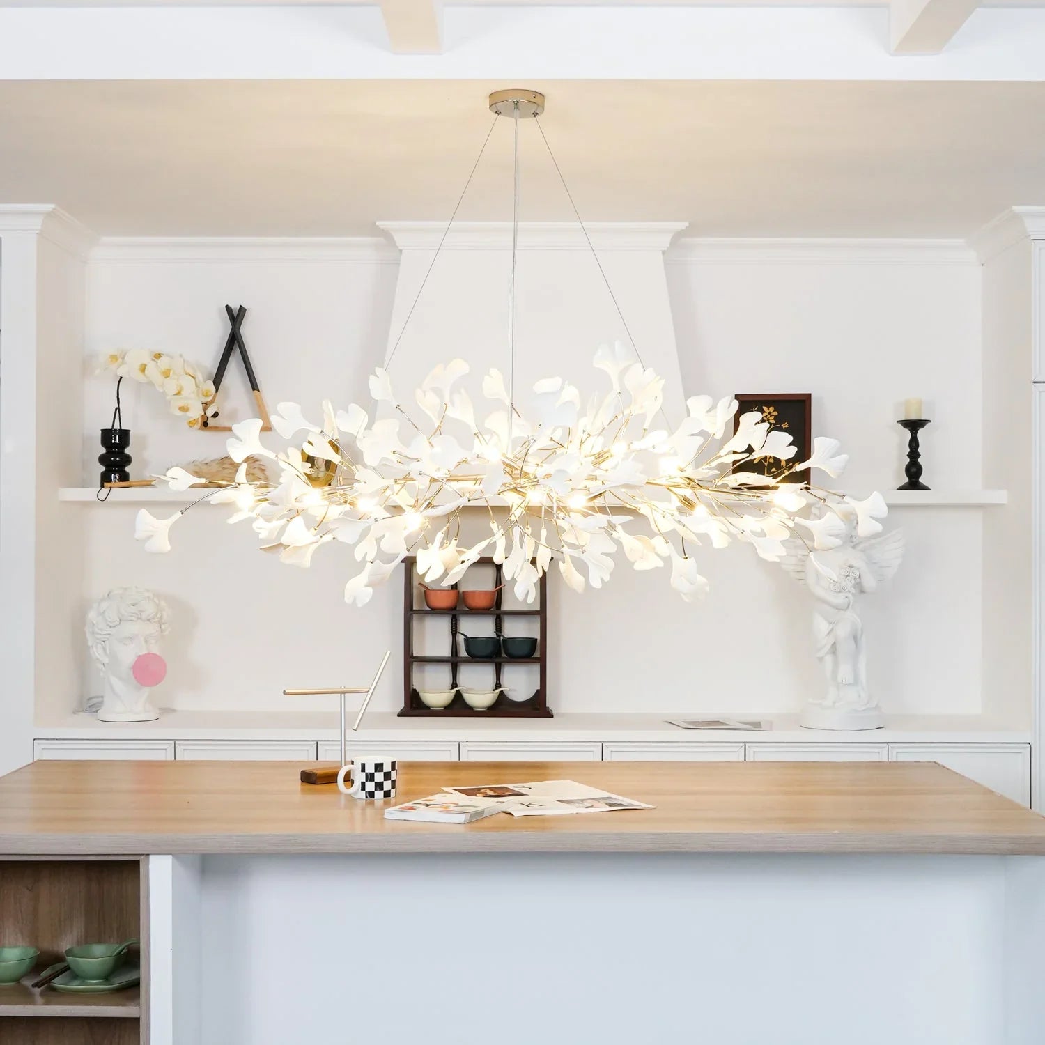 Modern gold and white gingko leaf chandelier pendant lamp above wooden kitchen island with white cabinetry