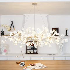 Modern gold and white gingko leaf chandelier pendant lamp hanging above wooden table in stylish interior