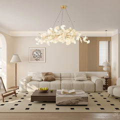Modern living room with beige sofa, wooden and marble coffee tables, art print, and gold-white Gingko chandelier
