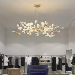 Modern gold and white gingko leaf chandelier pendant lamp in minimalist boutique with clothing racks and navy sofa