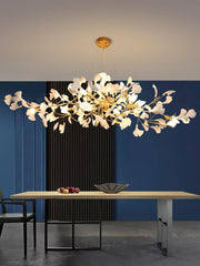 Modern gold and white ginkgo leaf chandelier pendant lamp over wooden dining table in contemporary room