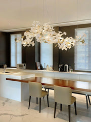 Modern kitchen with white and gold Gingko chandelier pendant light over wooden dining table and beige chairs