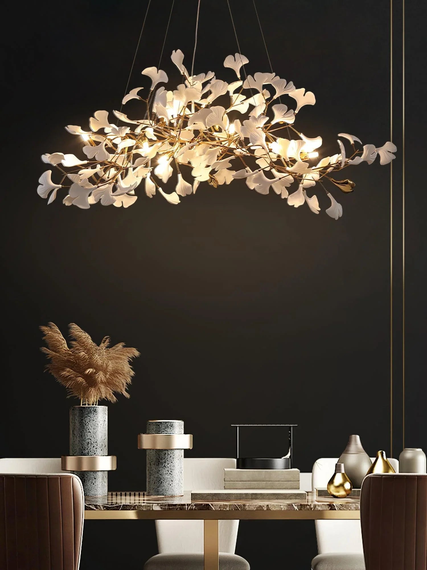 Modern gold and white gingko leaf chandelier pendant lamp over stylish dining table with vases and pampas grass