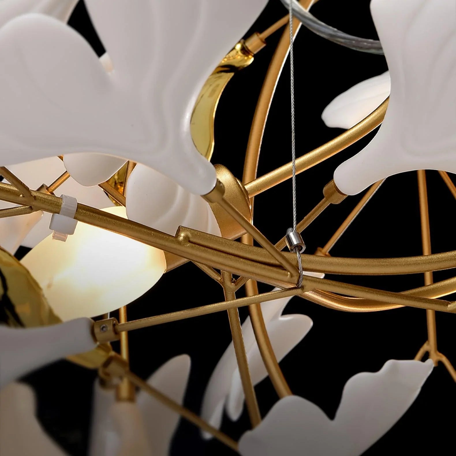 Close-up of modern gold pendant chandelier with white gingko leaf-shaped glass shades