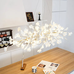 Modern gold and white Gingko pendant chandelier hanging above wooden dining table in a bright kitchen