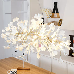 Modern gold and white ginkgo leaf chandelier pendant lamp hanging above wooden table in stylish kitchen