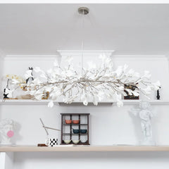 Modern gold and white ginkgo chandelier with delicate leaf design hanging above minimalist shelf decor