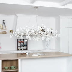 Modern white ginkgo leaf chandelier pendant lamp hanging above wooden kitchen island in bright minimalist room