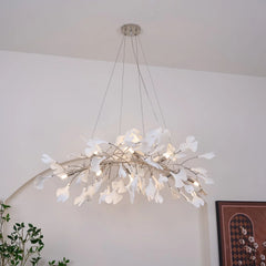 Modern white gingko leaf chandelier pendant lamp hanging in minimalist room with plant and framed art