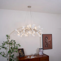 Modern gold and white gingko pendant chandelier hanging above wooden sideboard with plant and framed art