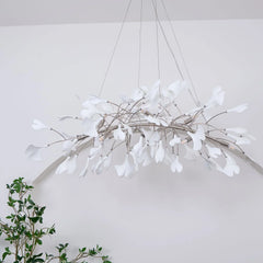 Modern gold and white pendant chandelier with ginkgo leaf design hanging in minimalist white room