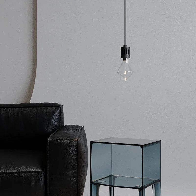 Modern pendant lamp with nickel finish above glass side table and black leather sofa