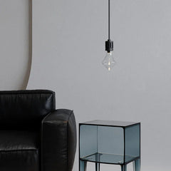 Modern pendant lamp with nickel finish above glass side table and black leather sofa