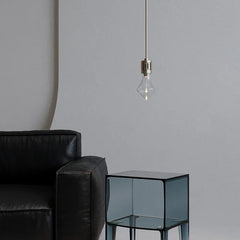 Modern pendant lamp with nickel finish above glass side table and black leather sofa