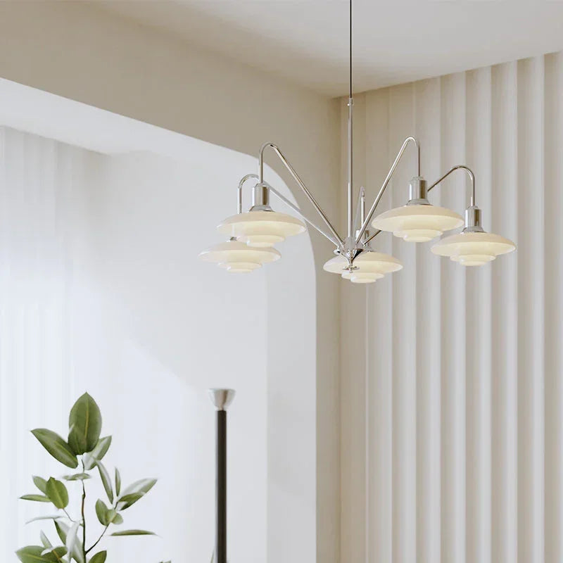 Modern silver chandelier with five layered glass shades in a bright, minimalist living room