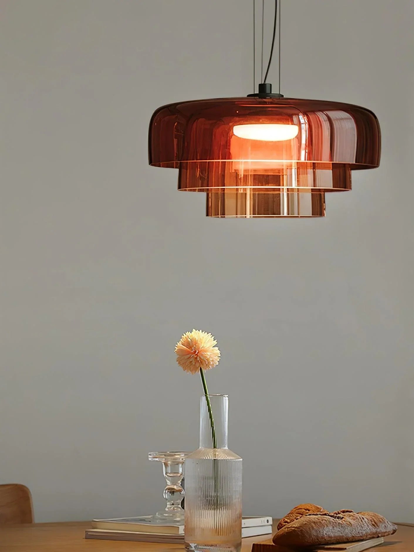 YH Lamps modern smoke grey pendant lamp with warm light, above a wooden table with flower vase and bread