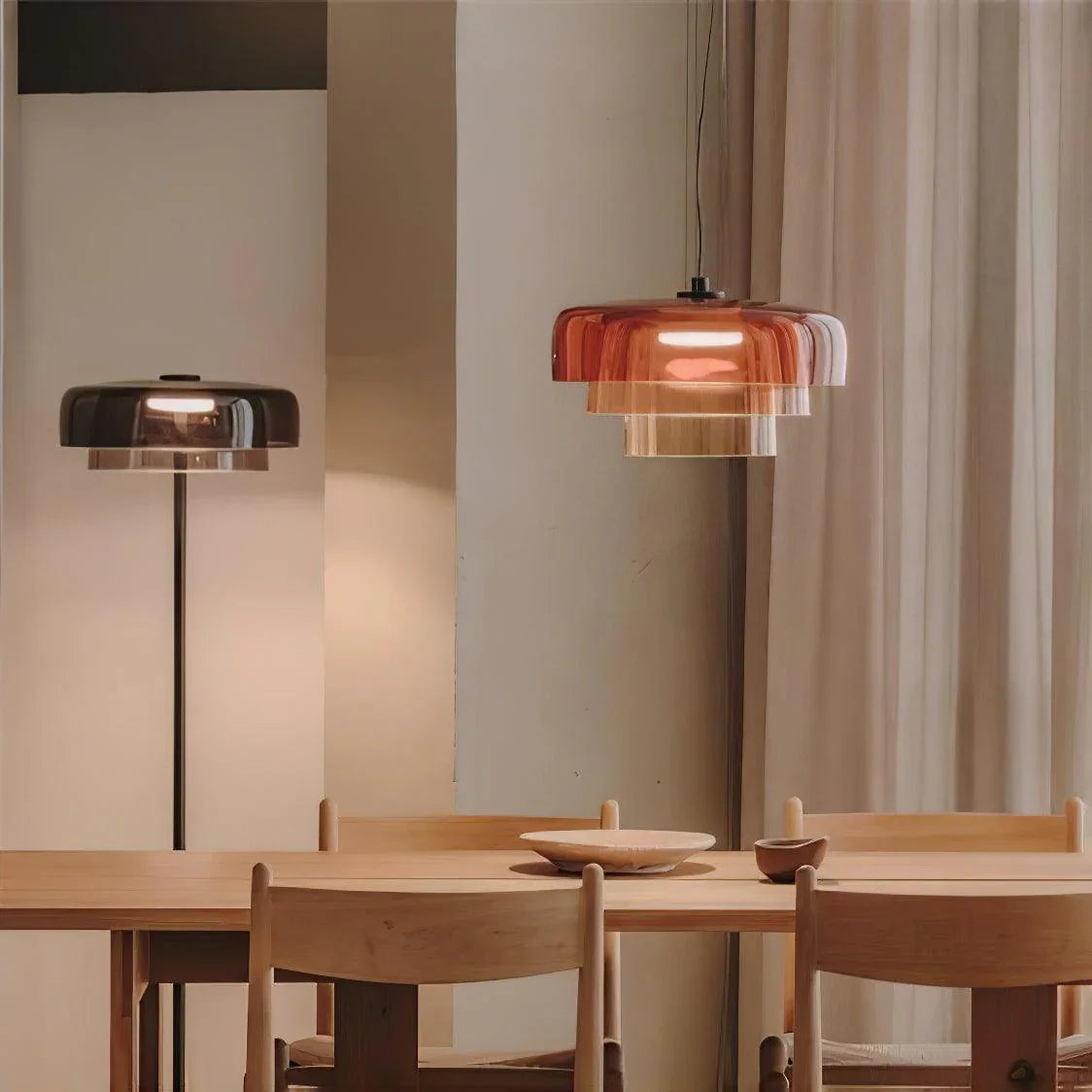 Modern dining room with wooden table and chairs, featuring a smoke grey floor lamp and amber layered glass pendant chandelier