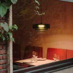 Modern smoke grey pendant lamp with warm light over restaurant table set with plates and glasses