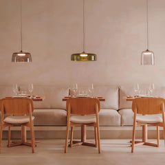 Modern dining area with three wooden chairs, beige cushioned bench, and three pendant lamps in smoke grey and warm light
