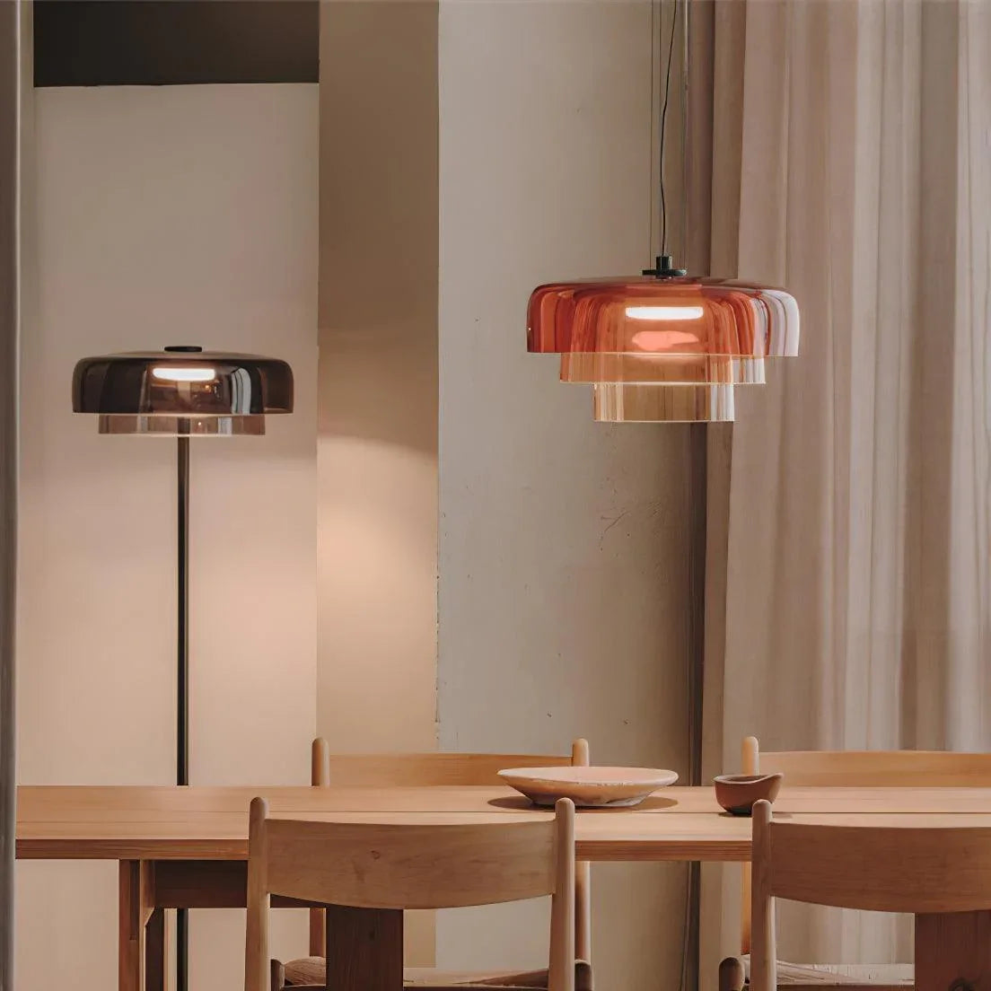 Modern smoke grey pendant lamp and matching floor lamp above wooden dining table with chairs in minimalist interior