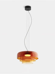 Modern amber glass layered pendant chandelier with warm light, suspended from black ceiling mount