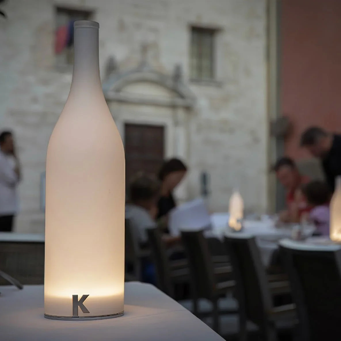 Modern white table lamp with bottle shape and warm light on a dining table, YH Lamps
