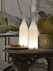 Modern white bottle-shaped table lamps with warm light on a decorative metal outdoor table, YH Lamps