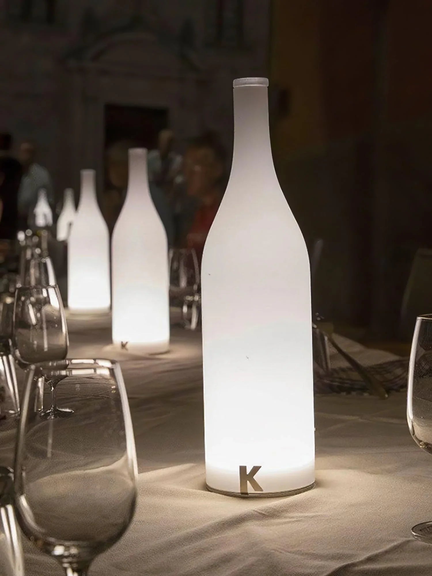 Modern bottle-shaped white table lamps with warm light on a dining table, YH Lamps