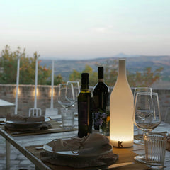 Modern white bottle-shaped table lamp with warm light on outdoor dining table, YH Lamps