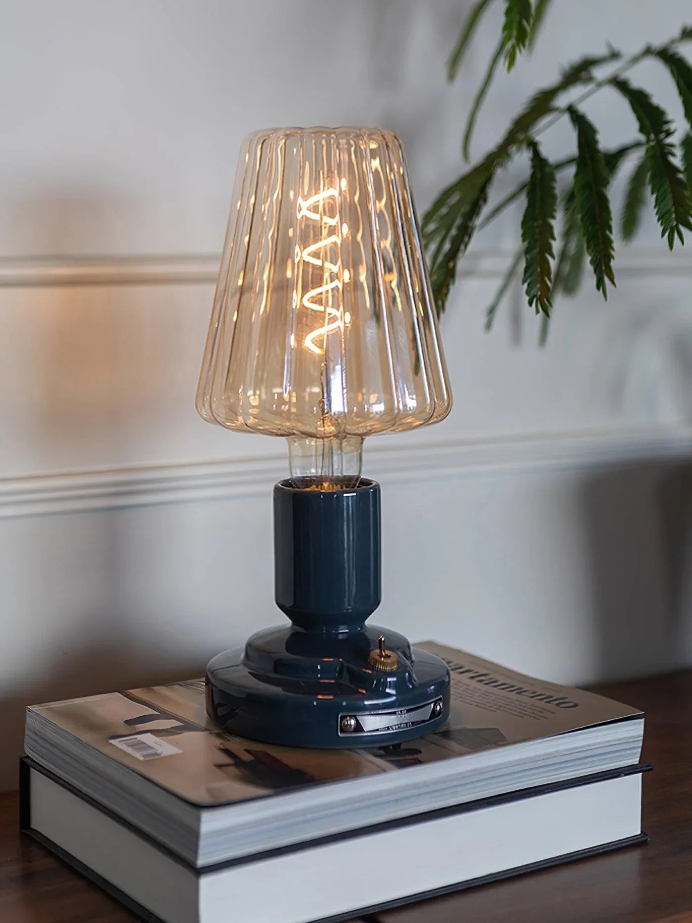 Modern black USB table lamp with glass shade, built-in battery, on books in stylish room