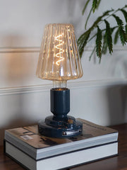 Modern black USB table lamp with glass shade, built-in battery, on books in stylish room