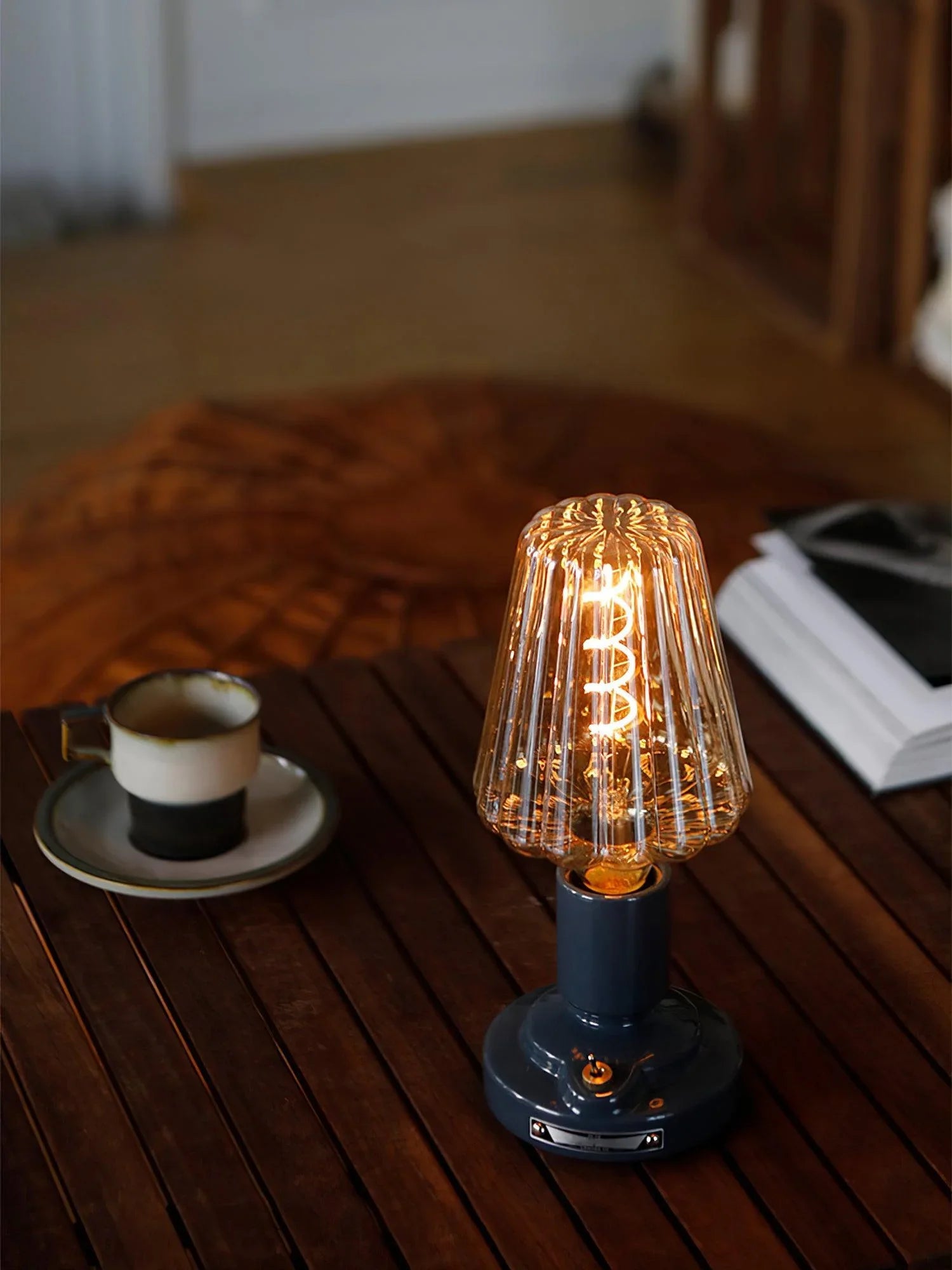 Modern black USB table lamp with ribbed glass shade on wooden table, coffee cup nearby