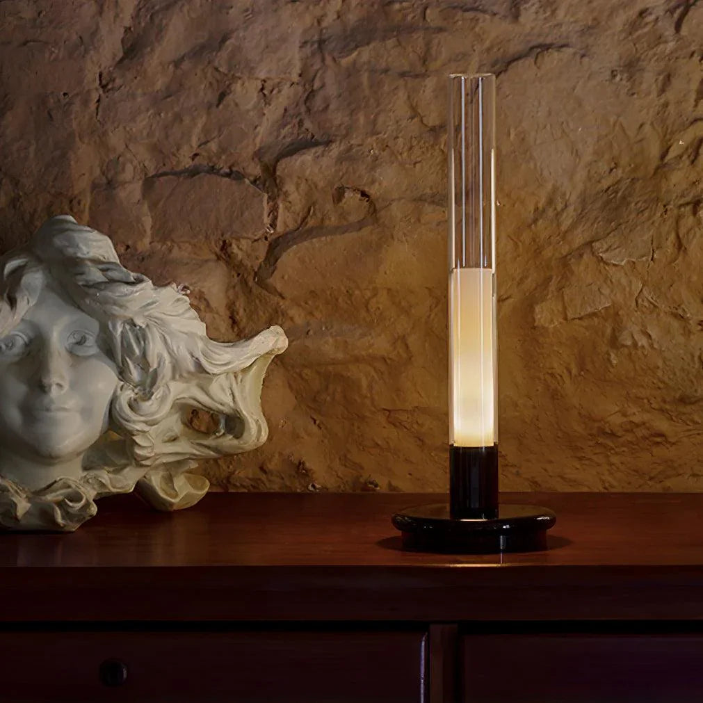 Modern column table lamp with warm light on wood dresser beside sculpted head, YH Lamps