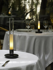 Modern black and clear column table lamp with warm light on a white table at YH Lamps