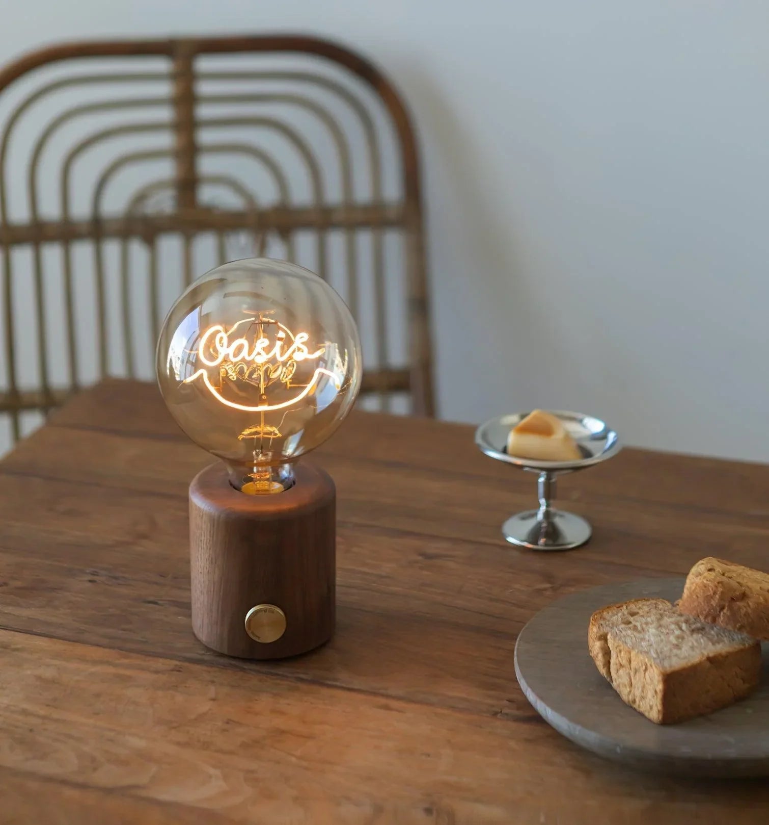 Modern walnut table lamp with round bulb reading 'Oasis' on wooden dining table