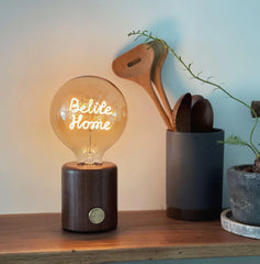 Modern YH Lamps walnut table lamp with glowing Believe Home text, on wooden shelf