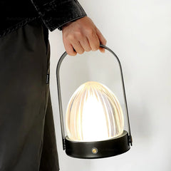 Modern black table lamp with built-in battery and touch switch, held by handle