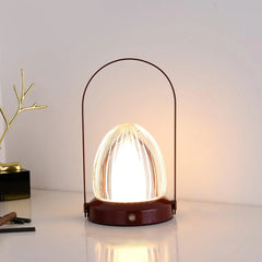 Modern egg-shaped table lamp with transparent glass shade and maroon base on a white desk
