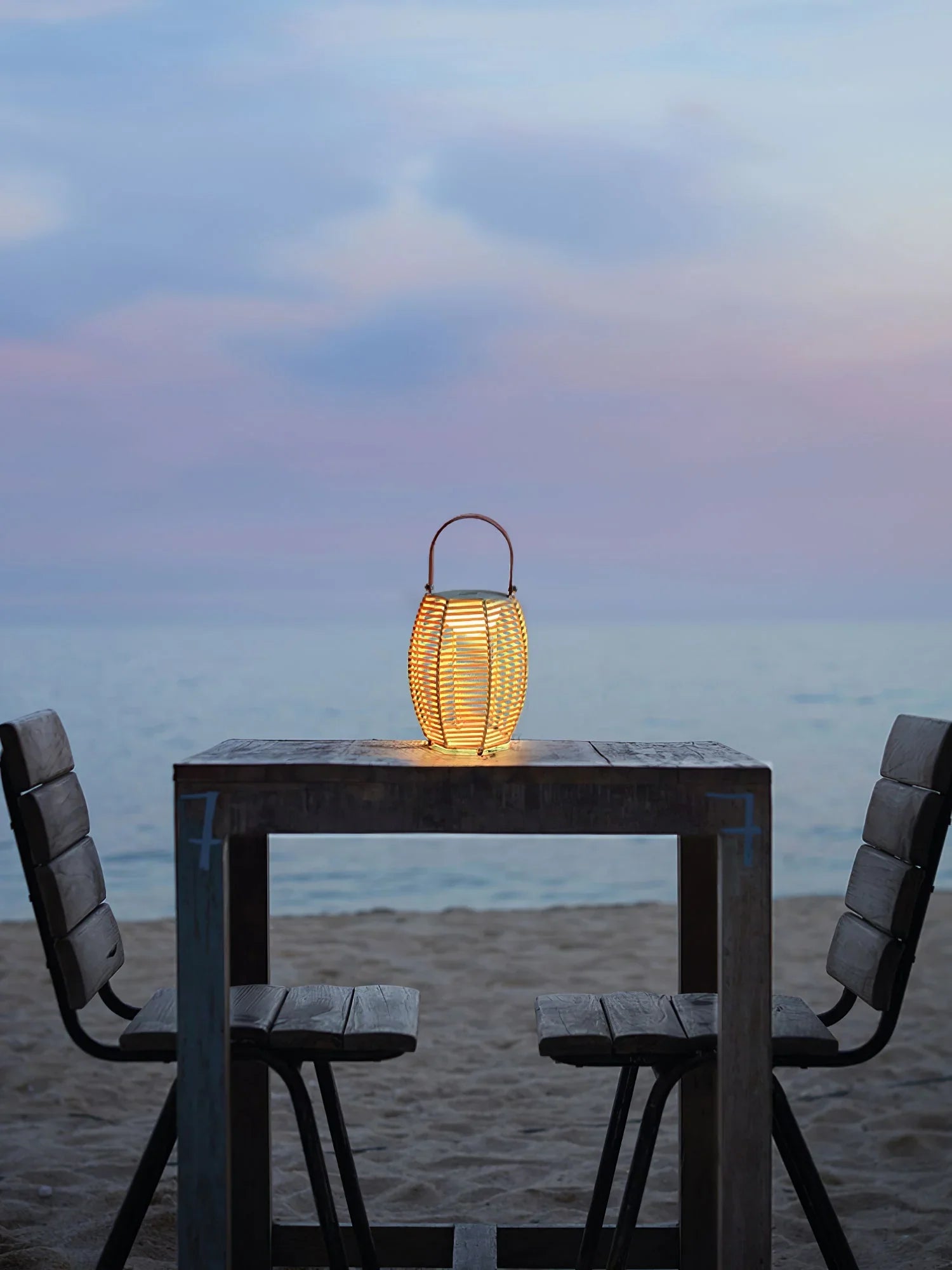 Modern yellow USB lantern table lamp on wooden beach table with two chairs at sunset, YH Lamps