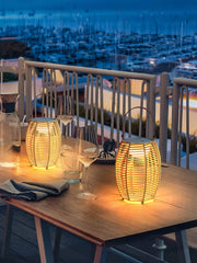 Yellow USB lantern table lamps with built-in battery on a wooden patio table at dusk.