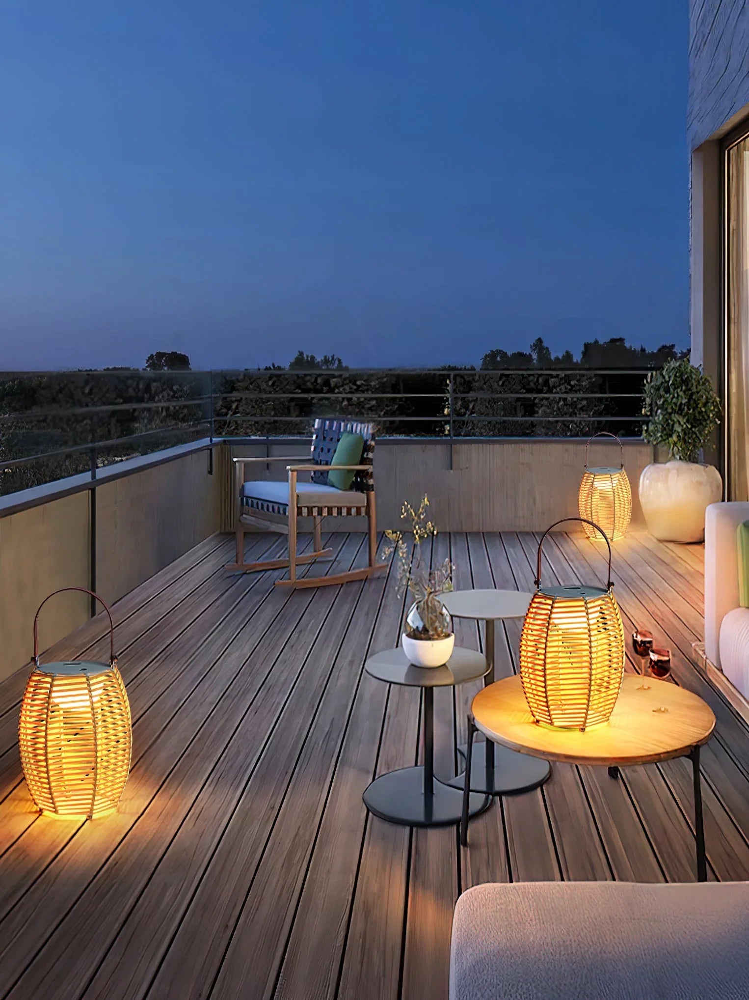 Modern outdoor patio with glowing yellow lantern table lamps by YH Lamps on wood deck