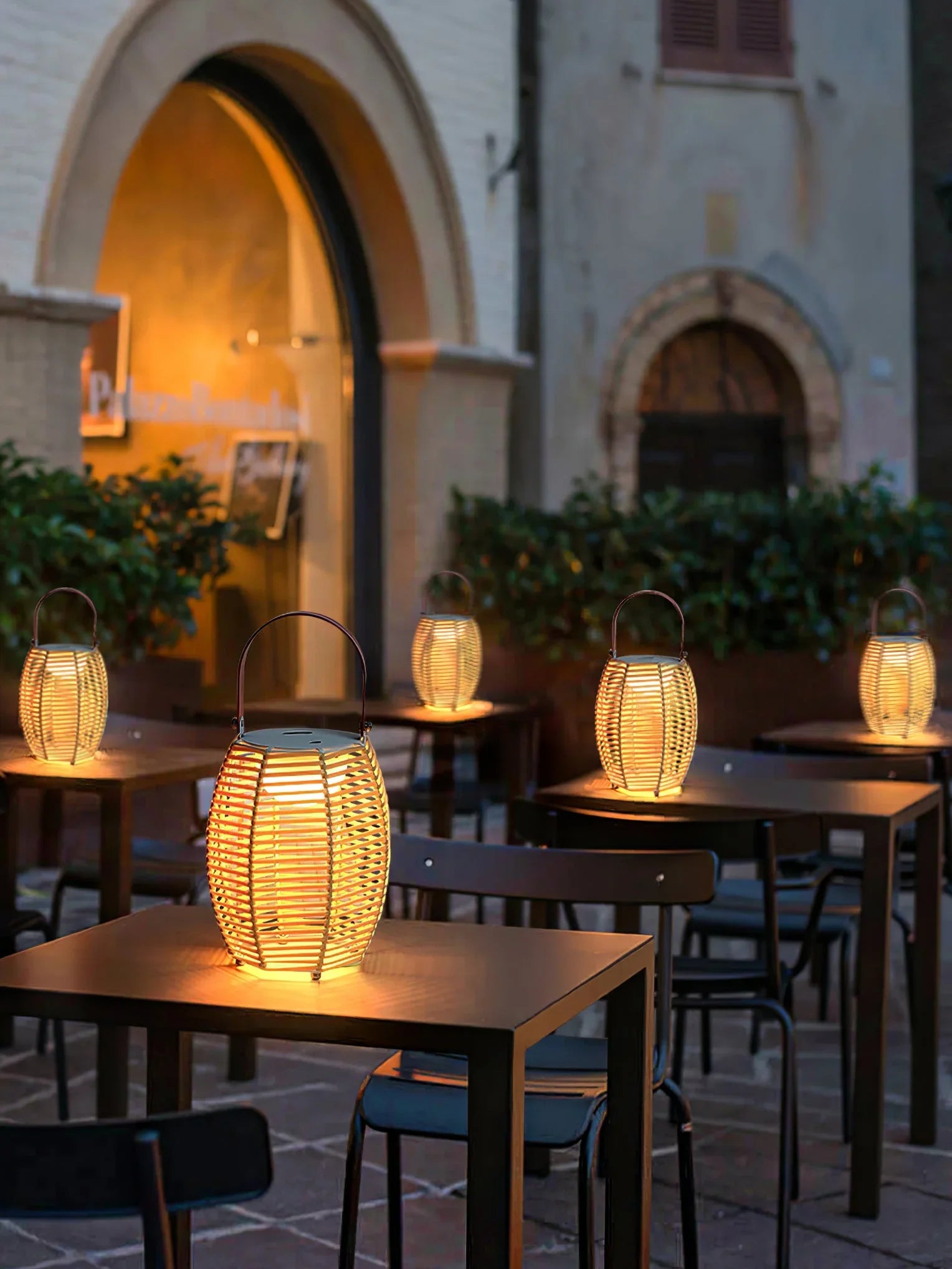 Modern yellow and white lantern table lamps on outdoor café tables, evening ambiance