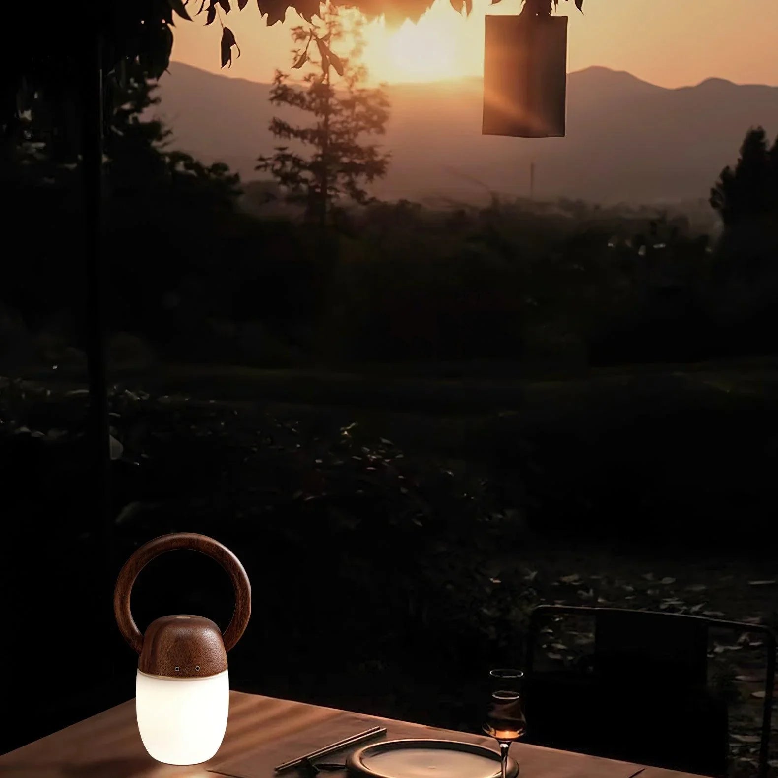 Modern wooden table lamp with warm light on an outdoor table at sunset, YH Lamps