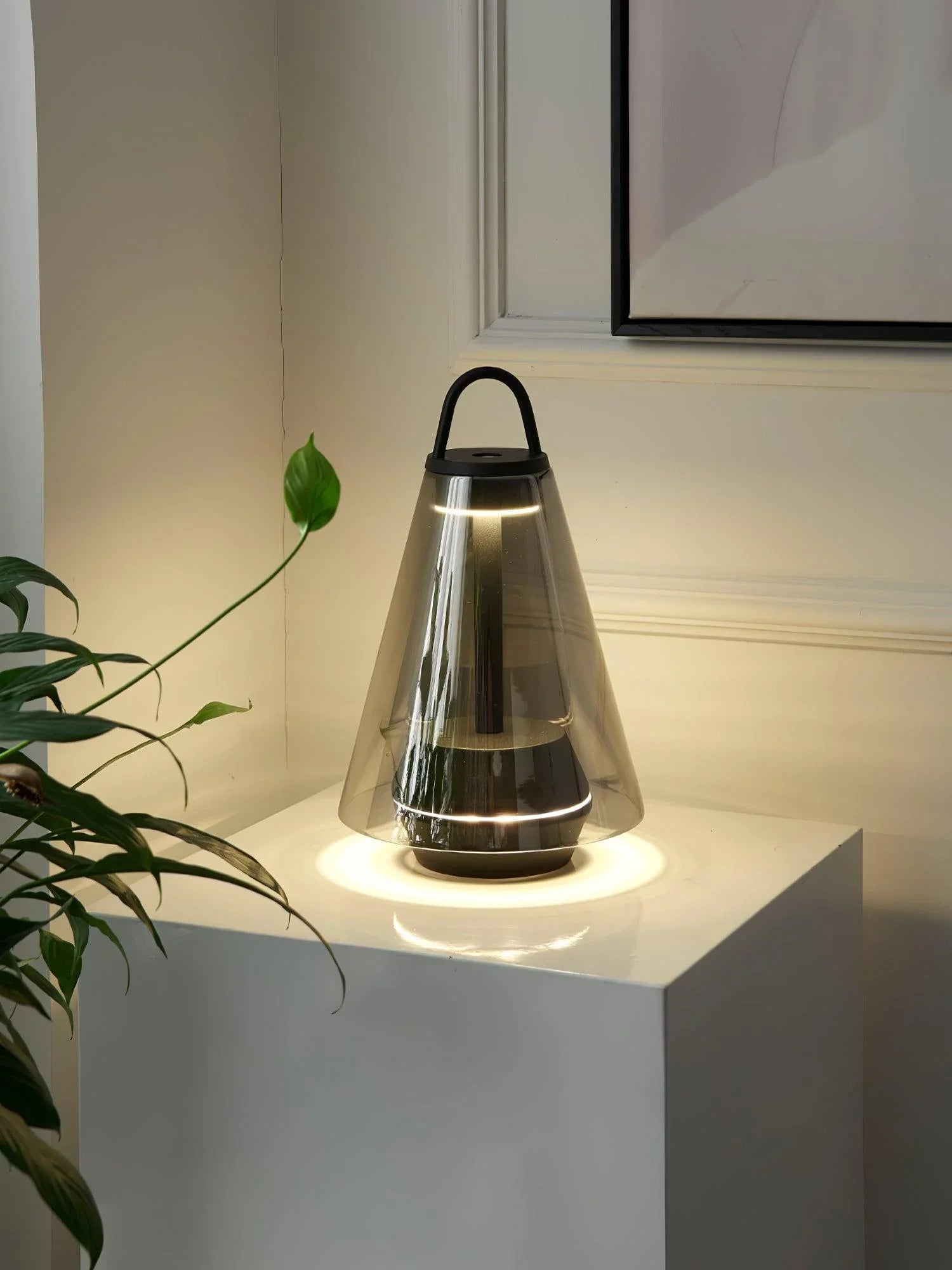 Modern black cone-shaped table lamp with clear glass and warm light on white pedestal at YH Lamps